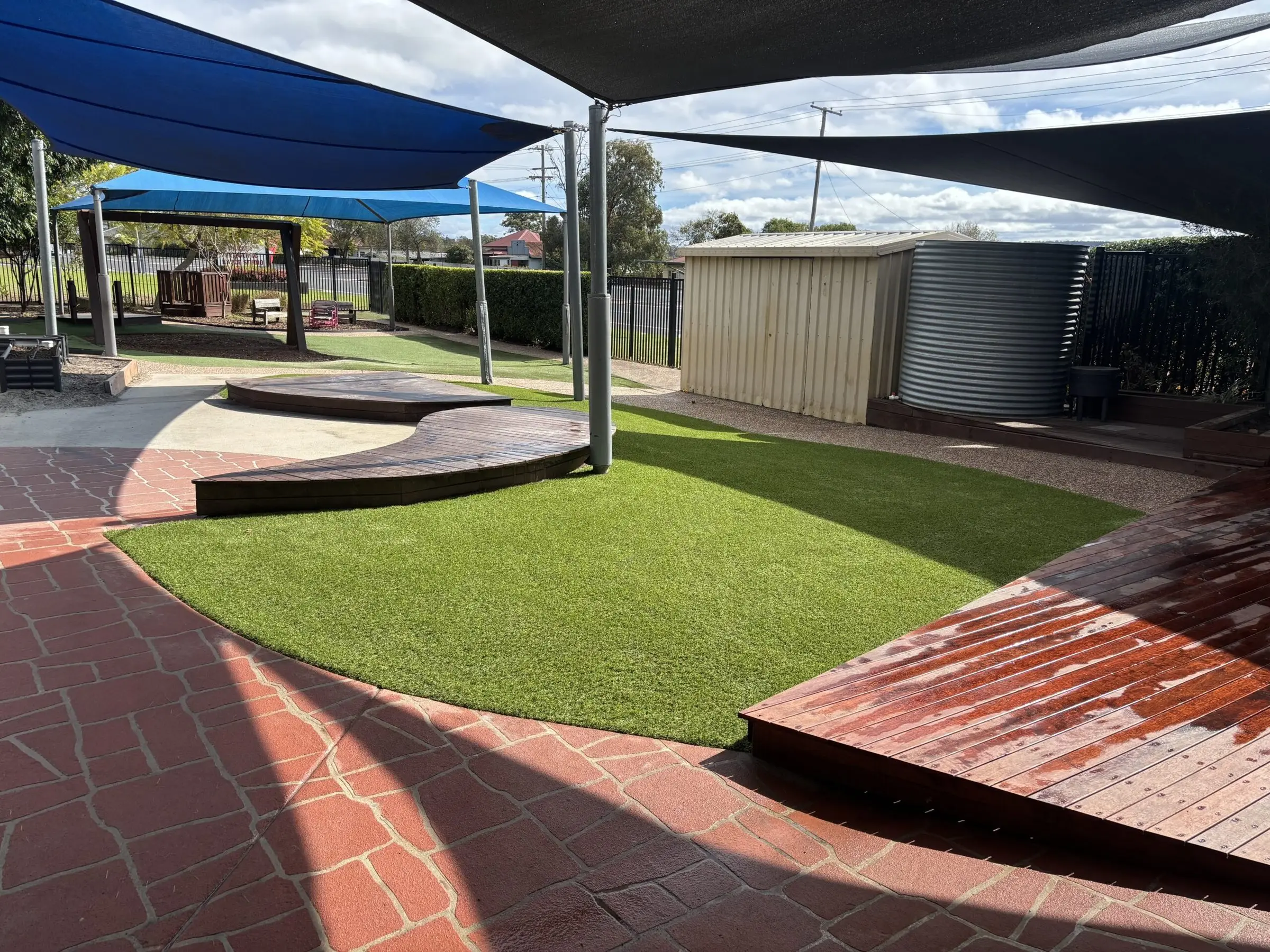Synthetic grass play yard with new shade sails and timber deck after works, Gatton childcare centre
