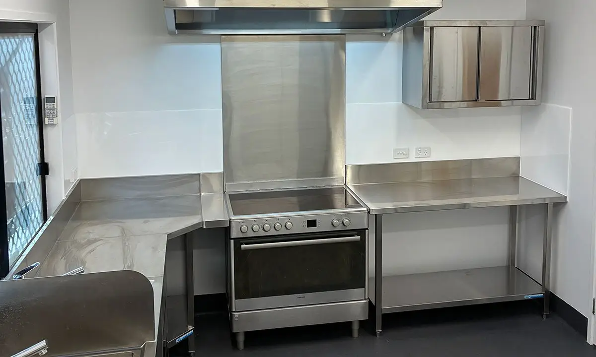 Upgraded commercial kitchen with stainless steel benches and range hood, Nundah childcare centre