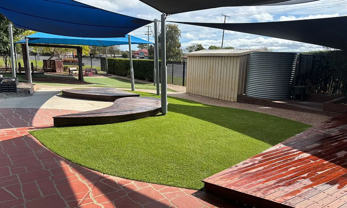 New synthetic grass with paved edge and timber deck under shade sails