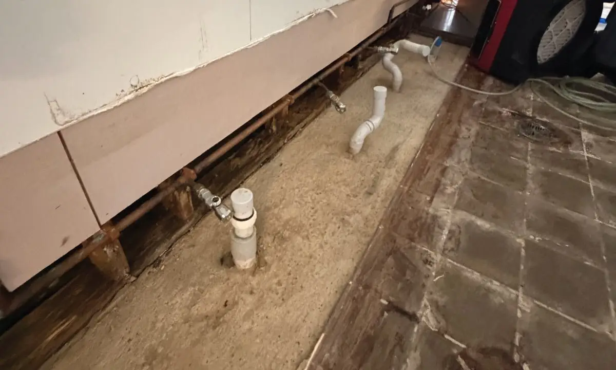 Bathroom stripped to the slab with exposed plumbing, Logan Reserve