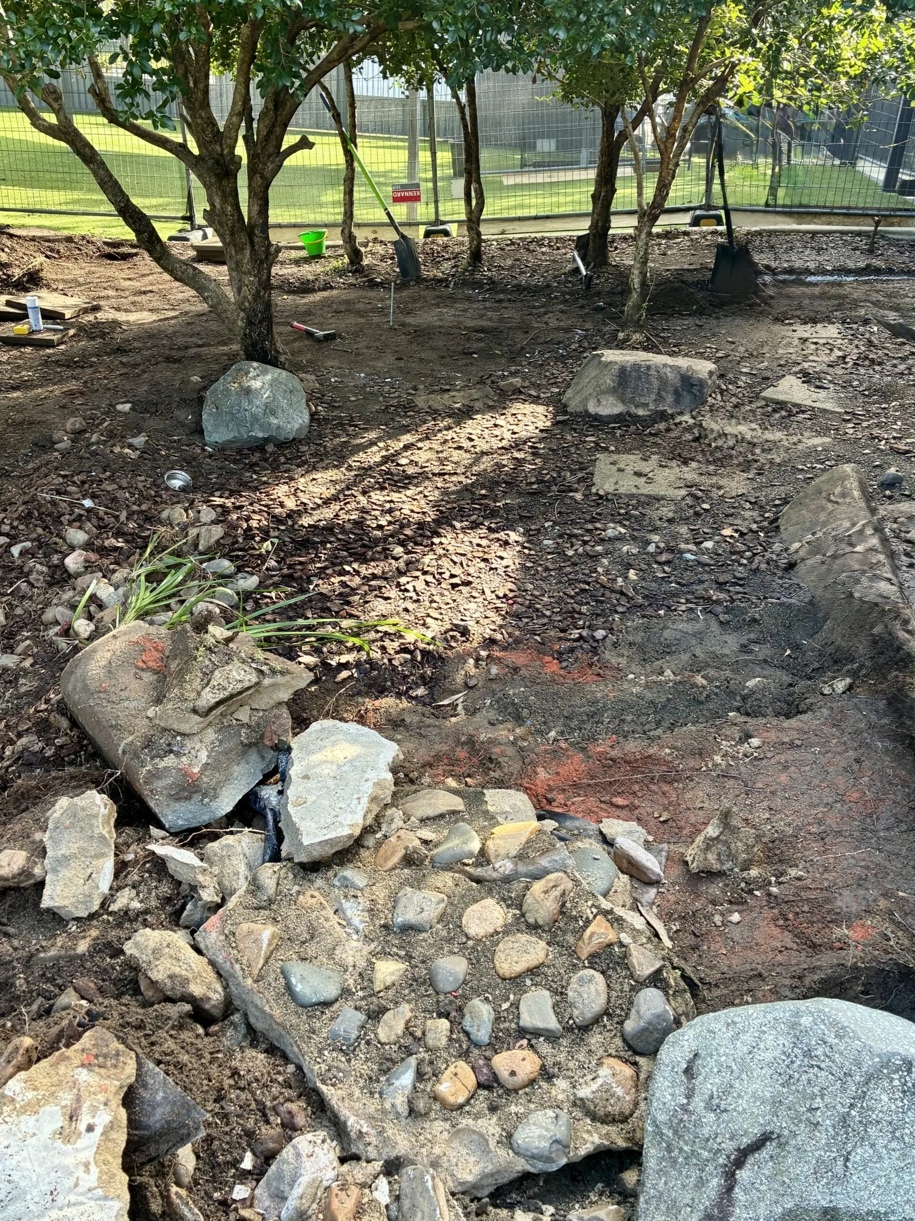 Overgrown dirt and rocks under a tree before the sandpit was built, Mackay