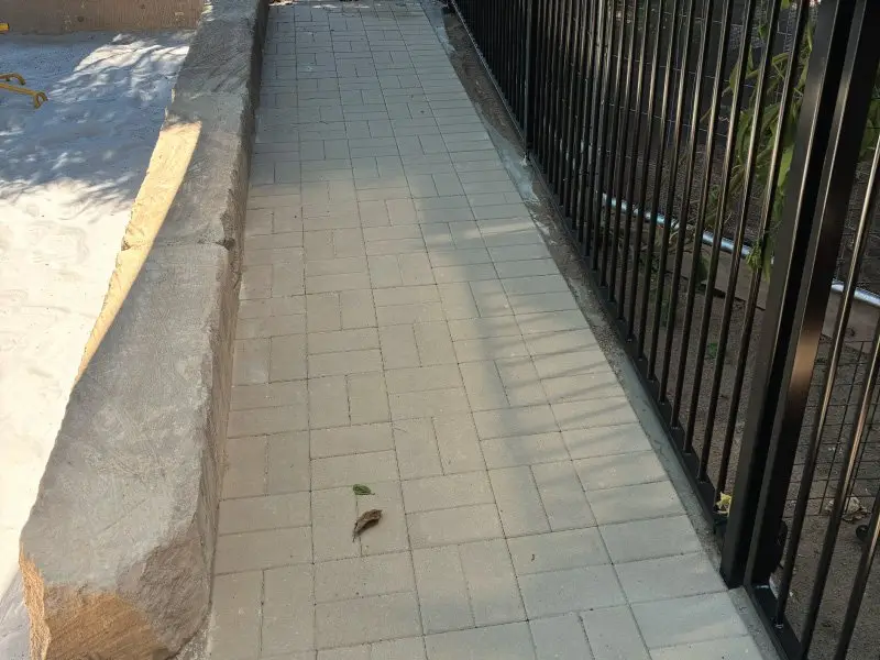 New paved path with retaining edge beside the yard fence