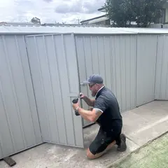 Fixed tradesperson installing a garden shed at a childcare centre