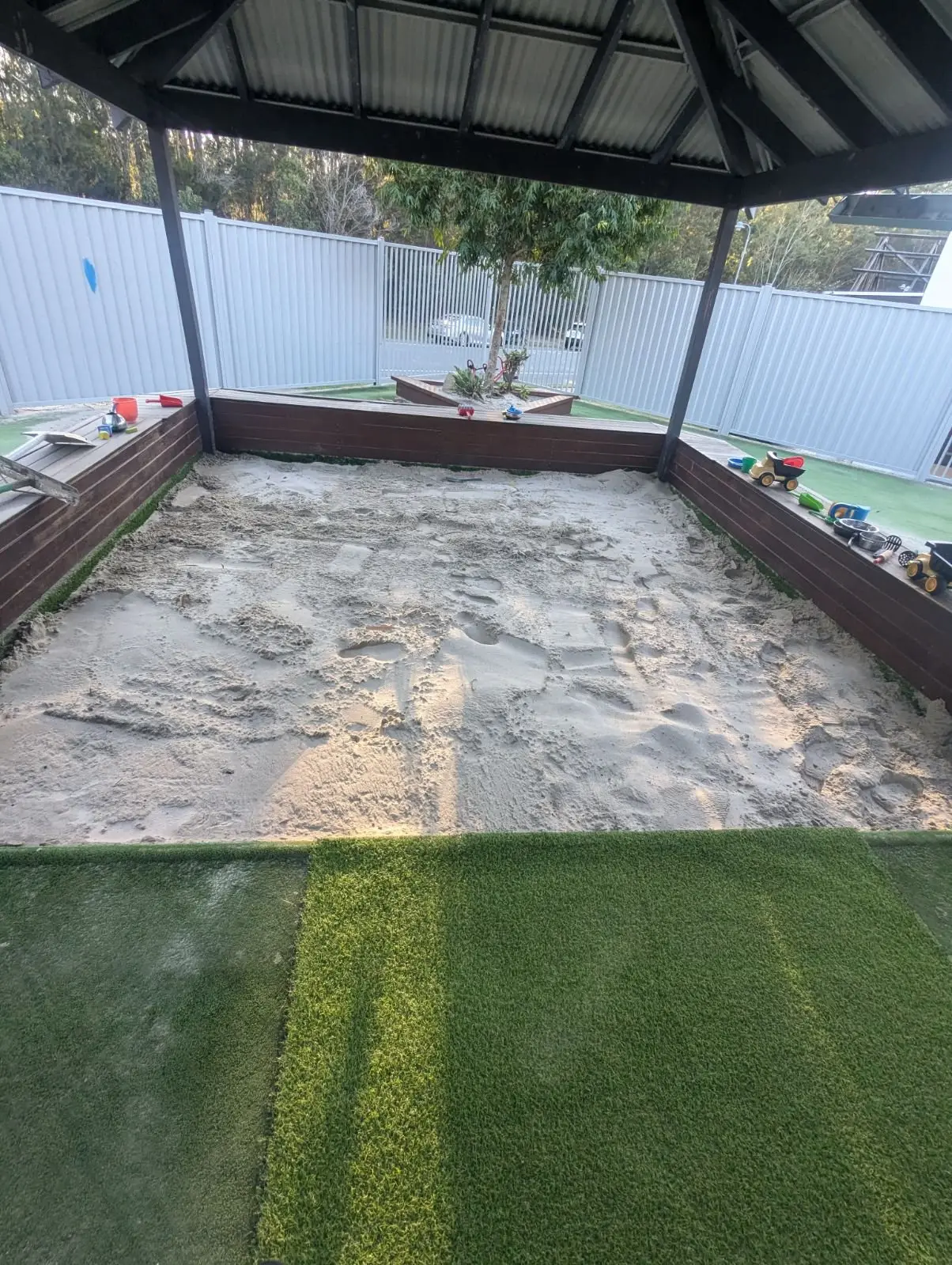 Sandpit top-up under a shade structure at a childcare centre