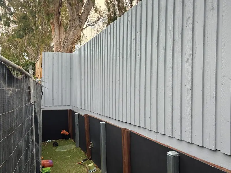 New Colorbond fence above a dark retaining wall along the yard boundary