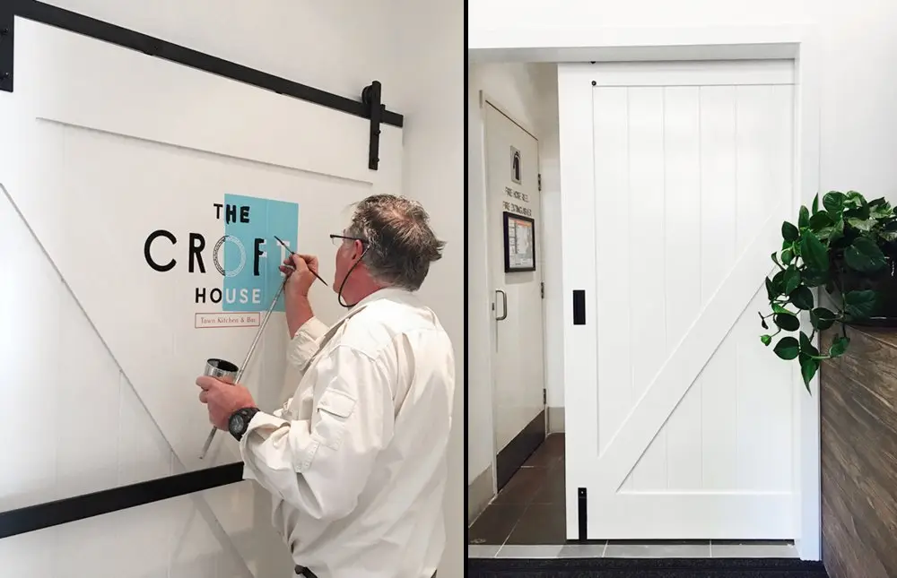 Custom wrought-iron barn door with the Croft House sign being painted