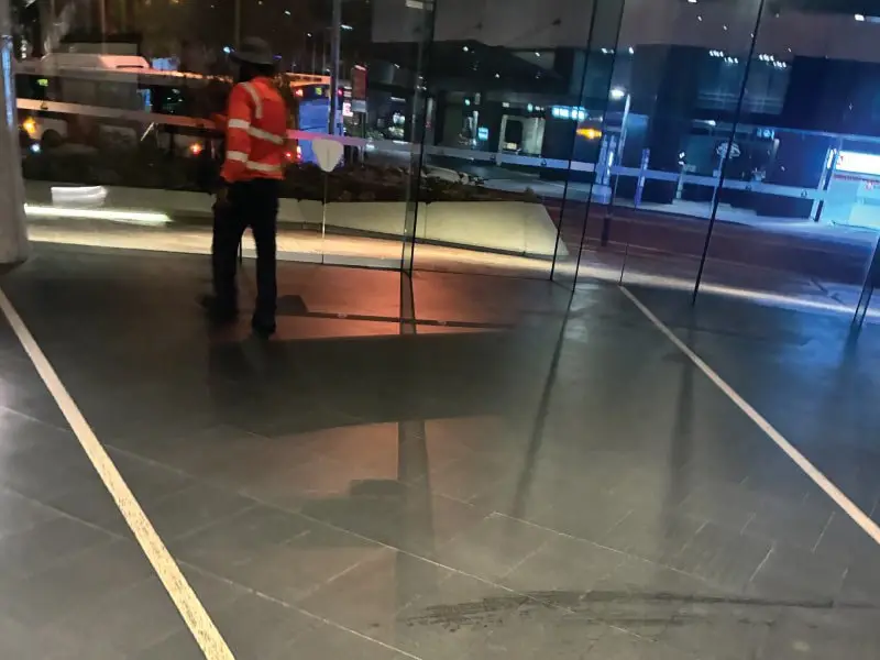 Tradesperson in high-visibility vest beside the foyer glass at night
