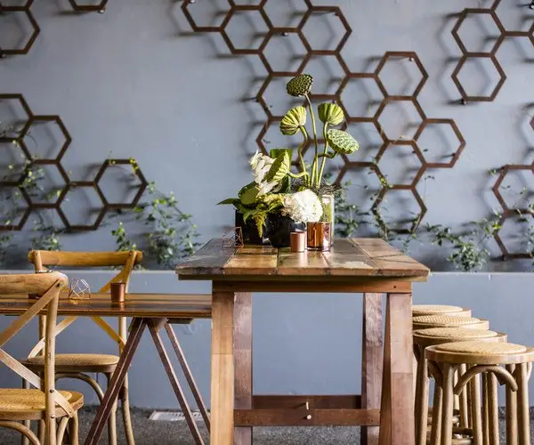 Hexagon wall art and a timber bar table with stools in the laneway