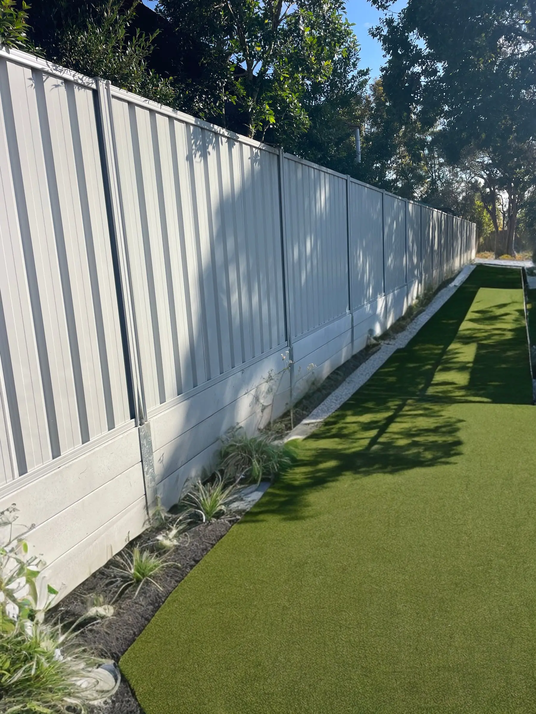 Concrete sleeper retaining wall with Colorbond fencing and new garden bed at a childcare centre