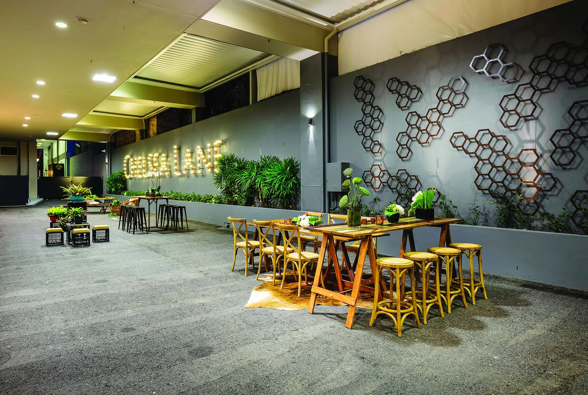 Long view of Chelsea Lane with timber tables, stools and the lit sign