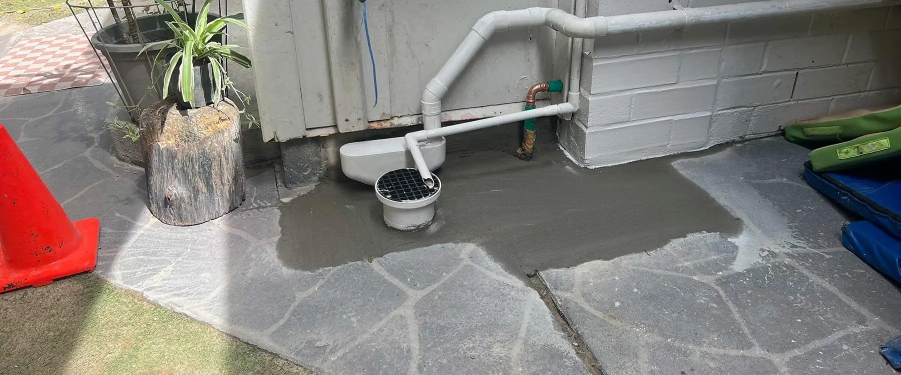 Repaired drain and pipework on a flagstone path at a childcare centre